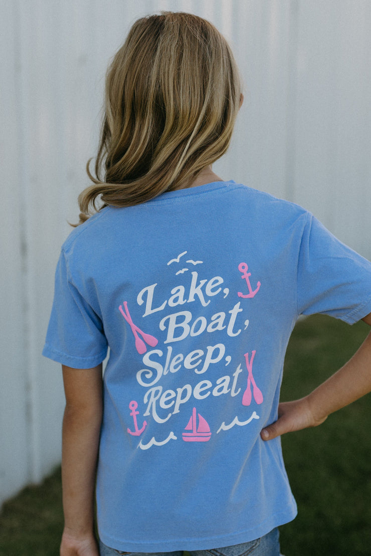Young girl wearing a peri t-shirt with 'Lake, Boat, Sleep, Repeat' text and graphics.