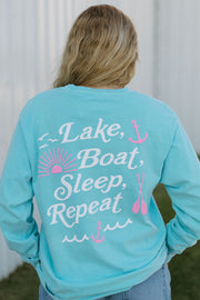 Person wearing a turquoise long-sleeve shirt with 'Lake, Boat, Sleep, Repeat' text.