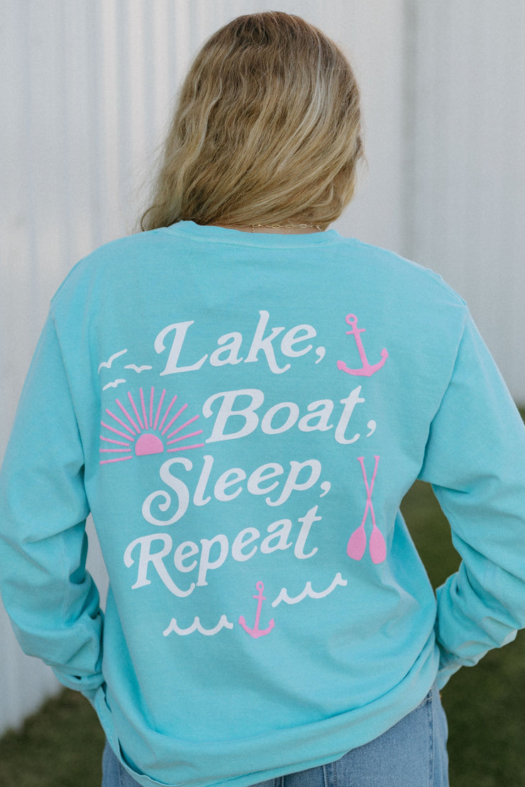 Person wearing a turquoise long-sleeve shirt with 'Lake, Boat, Sleep, Repeat' text.