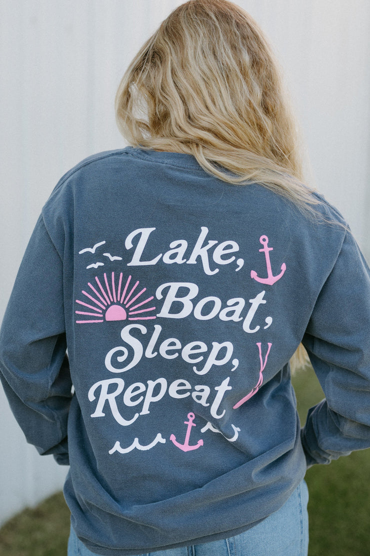 Woman wearing a sweatshirt with 'Lake, Boat, Sleep, Repeat' text on the back.
