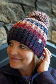 Person wearing a colorful knit hat in front of a stone wall