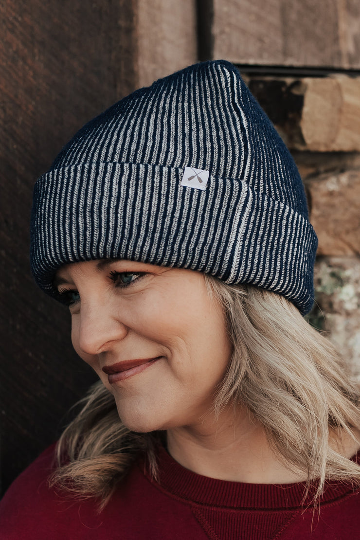Woman wearing a ribbed beanie and red sweater against a stone wall.