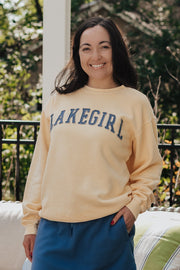 Woman wearing a 'Lakegirl' sweatshirt standing outdoors with a couch and plants in the background